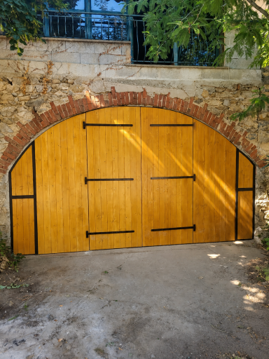 Porte de garage Porte de garage en épicéa à double battant sous un arc en pierre